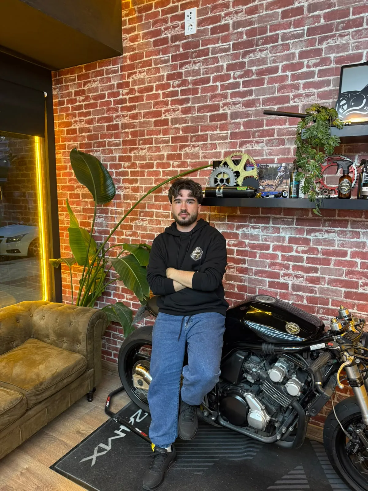 Alejandro “Herrera”, barbero de 2 Stroke Barbershop en Fuenlabrada, junto a la moto del local