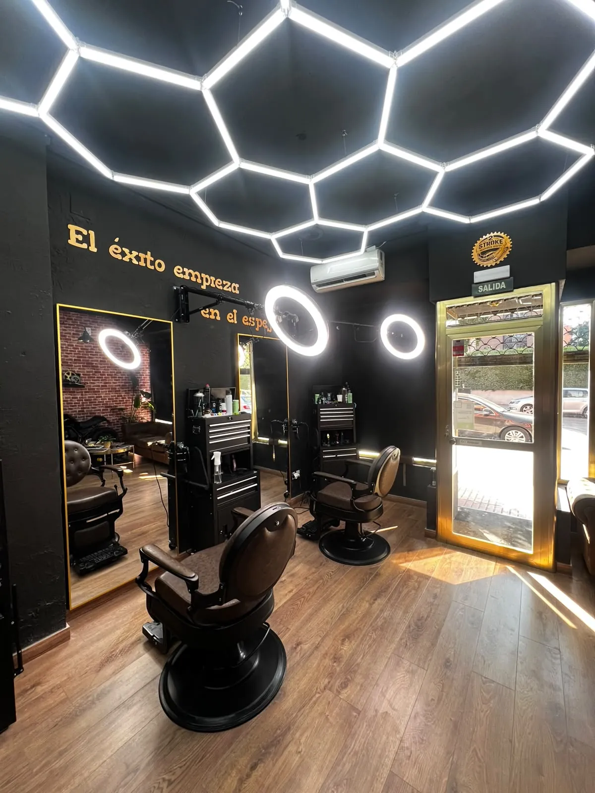 Interior de la barbería 2 Stroke en Fuenlabrada con luces hexagonales, sillones de barbero y espejos