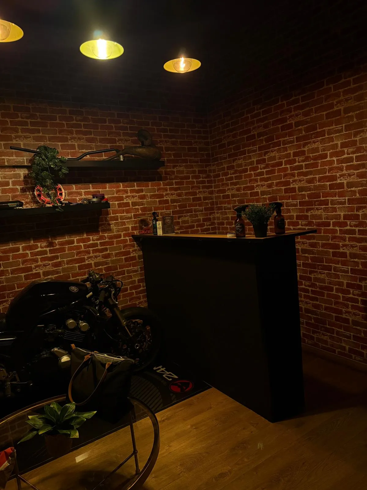 Zona de espera con pared de ladrillo y luces industriales en la barbería de Fuenlabrada